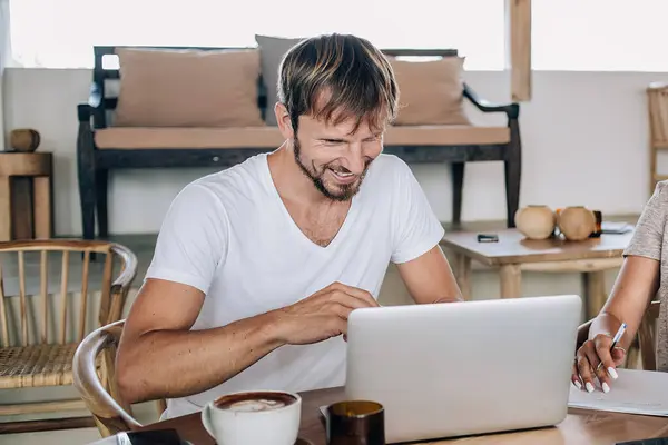 Bali kafeteryasında sevinen neşeli beyaz erkek ve kadın, Endonezya 'daki internete bağlanıp bilgisayarla uzaktan kumanda yapıyorlar, mutlu erkek ve kadın internet sitesinden komik videolar izliyorlar.