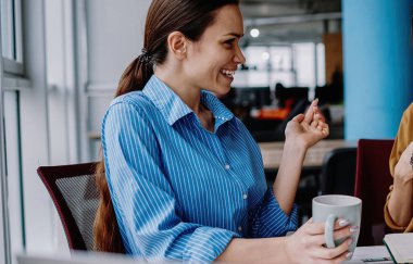 Kafkas kadın çalışanlar kahve molasında iletişim kurarken eğleniyorlar. Refah içinde çalışan kadınlar birbirleriyle konuşuyorlar. Masaüstünde birlikte oturmaktan memnun görünüyorlar.