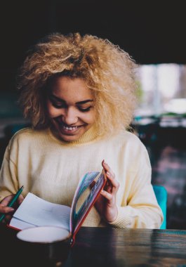 Mutlu Afro-Amerikan bayan öğrenci gülümseyerek ders kitaplarında eğitim için bilgi ararken, pozitif esmer tenli hippi kız otokopi çekerken eğleniyor.