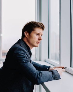 Resmi giyinmiş, beyaz tenli bir işadamı, ofisteki işi düşünmekten vazgeçiyor. Düşünceli, yakışıklı, finans şirketinin sahibi. Takım elbise giymiş, proje üzerinde kafa yoruyor.