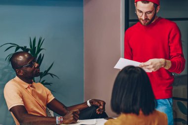Şirket meslektaşları, çok ırklı erkek ve kadın grupları ile yapılan toplantıda ciddi bir takım lideri, koçun ofiste mali planlamayı kontrol edişini dinliyor.