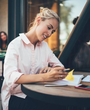 Modern başarılı kadının yan görünüşü, kahve dükkanının terasında oturan ve günlük notlarını kontrol ederken gün için planlar yapan...