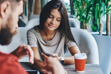 Buluşmada modern dijital cihazlar kullanarak numaralarını değiştiren erkek ve kadın meslektaşlarının kesilen görüntüleri, genç kadın bluetooth aracılığıyla bluetooth aracılığıyla hipster adamla kafede konuşurken multimedya dosyalarını paylaşıyor.