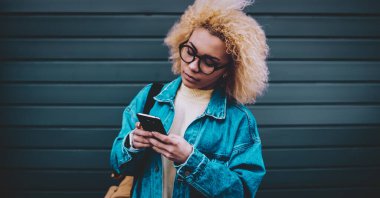 4G kablosuz interneti taramak ve web sitesinde takipçilerle sohbet etmek için şık giyinmiş Afro-Amerikalı hippi kız, çekici bayan öğrenci medya dosyası