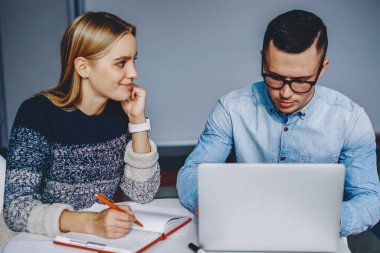 Ödev yazan ve gelecek sınavlara dizüstü bilgisayar ve internet bağlantısını kullanarak hazırlanan iki yetenekli öğrenci. Masaüstünde bilgisayarla oturan ortak proje üzerinde çalışan profesyonel tasarımcılar