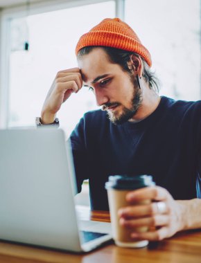 Kafkas erkek öğrenci yorgun hissediyor web sayfasında internete bağlı dizüstü bilgisayarla sıkıcı eğitim webinar izlerken, yetenekli serbest yazar web sitesinde yararlı makaleler okuyor