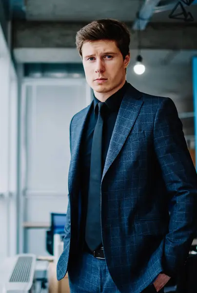 Half length portrait of confident man owner of company in formal wear standing in office, handsome serious caucasian male entrepreneur dressed in elegant suit looking at camera thoughtfully