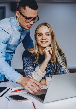 Dizüstü bilgisayardaki internet bağlantısını kullanarak tasarım projesinde iş birliği yaparken kameraya gülümseyen neşeli yeniyetme kızın portresi. Netbook 'ta işbirliği yapan iki bilişim uzmanı.