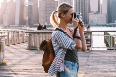 Beyaz kadın avare ellerinde kamerayla Amerikan görüşünün birkaç fotoğrafını çekiyor. Yolculuk sırasında kamerayı test eden yetenekli bayan gezgin ekipmanları.