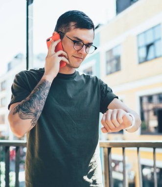 Beyaz çağdan kalma hippi adam arkadaşınla buluşmayı beklerken takılabilir akıllı saati kontrol ediyor ve detayları soruyor. Gözlüklü genç adam iletişim kurmak için dolaşım bağlantısını kullanıyor.