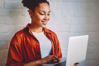 Koyu tenli hippi kız, modern dizüstü bilgisayarda kablosuz internete bağlıyken kendini iyi hisseden bir e-posta aldı. İndirme için film arayan ve boş zamanlarında izleyerek gülümseyen Afrikalı kadın.