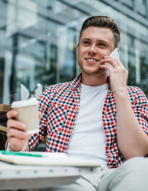 Ekose gömlekli, yakışıklı, sıradan bir adamın kahve içip caddede oturarak telefonda konuşmasından.