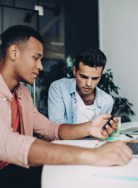 Akıllı telefon aygıtıyla online video izleyen çeşitli erkek çalışanlar masaüstünde bilgisayarlarla oturuyor, birlikte haberleşmenin keyfini çıkaran zeki meslektaşlar web sitesinde 4G 'ye bağlı haberleri okuyorlar.