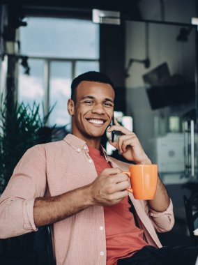 Profesyonel iş arkadaşı teknoloji konseptiyle, akıllı telefon cihazıyla iletişimin keyfini çıkaran neşeli erkek yazılım geliştiricisinin portresi