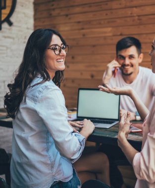 Gülen kadınlar el kol hareketleri yapıp iş hakkında tartışırken aynı anda açık kafedeki masanın etrafında oturan erkek arkadaşlarıyla buluşuyorlar.