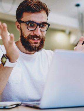 Gözlüklü, gülümseyen hippi, online yarışmayı kazanmaktan mutlu. Dizüstü bilgisayardan bildirimi kontrol ediyor. Kafkasyalı, serbest çalışan, online kazançlardan memnun.