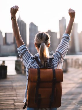 Sırt çantasında sırt çantasıyla başarılı kadın turistlerin el kaldırması ve megalopolis 'i keşfettiği için seyahat zaferini kutlaması. New York, Amerikan başarısından zevk alan başarılı kadın.