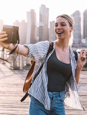 Geçmişe dönük teknolojisi olan mutlu kadın gezgin, arka planda Manhattan bölgesiyle selfie çekerken Amerika Birleşik Devletleri 'nde tatil yaparken eğleniyor.