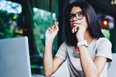 Gözlüklü düşünceli bir kadın kafenin iç kısımlarında dizüstü bilgisayarla çalışan blog fikri üzerinde kafa yoruyor. Düşünceli genç bir kadın netbook aracılığıyla uzaktan kumandayla düşünüyor.