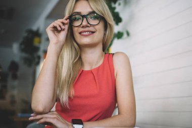 Aşağıdaki memnun genç bayan çalışanın kameraya bakması ve gözlüklere dokunması deftere bakıp kafede oturması.