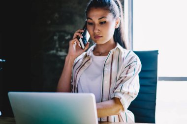 Ciddi bir kadın dizüstü bilgisayara yeni bir uygulama yüklüyor müşteri destek operatörüyle cep telefonu görüşmesi yapıyor talimatlar veriyor, kadın bankacılık bakiyesini kontrol ediyor ve hücresel danışmanlık sorununu çözüyor