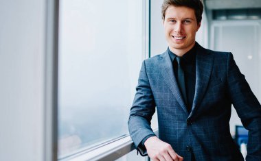 Seçkin takım elbiseli, resmi giyinmiş, başarılı bir iş adamı olarak iş hayatındaki başarısından memnun kameraya bakan zengin, beyaz tenli, şirketin sahibi erkek portresinin yarısı kadar.