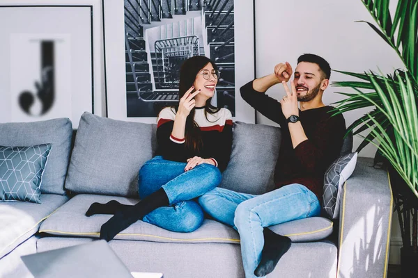 Happy family resting on comfortable couch in living room and feeling excited during positive conversation with each other, cheerful man and woman enjoying from spending leisure time togetherness