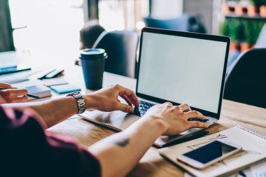 Ofiste kablosuz internet bağlantısı kullanarak modern bilgisayar kurma uygulamasında erkek ellerinin klavye kullanımının kırpılmış görüntüsü. Tasarım web sitemiz için dizüstü boş ekran alanıyla dizüstü bilgisayarda yazı yazan adam