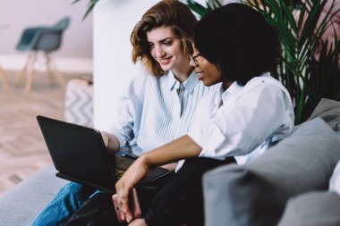 İki farklı arkadaş rahat kanepede rahatlıyor ve ev kablosuz interneti kullanarak dizüstü bilgisayarda film izliyorlar. Çok kültürlü genç kadınlar ortak bloglarında birlikte çalışıyorlar.