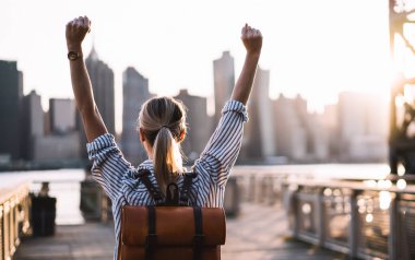 Sırt çantasında sırt çantasıyla başarılı kadın turistlerin el kaldırması ve megalopolis 'i keşfettiği için seyahat zaferini kutlaması. New York, Amerikan başarısından zevk alan başarılı kadın.