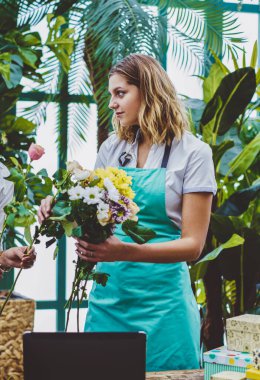 Mutlu çok kültürlü kadın çiçekçiler birlikte çiçeklerin kompozisyonu sırasında birlikte çalışmaktan zevk alıyorlar. Olumlu kadınlar yeşillikte vakit geçiriyorlar. Bahçıvanlık kavramı.