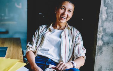 Dizüstü bilgisayarın yanında oturan neşeli başarılı kadın serbest yazar online iş dünyasından gelen gelirle tatmin olmuş, gülen kadın blogcu ofisteki makale için komik bir fikre gülüyor.