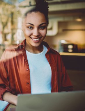 Mutlu kız öğrenci portresi e-öğrenim için çalışma alanında zaman harcıyor ve kolej dersi için bilgi araştırması yapıyor modern dizüstü bilgisayarla oturuyor, otodiktat konsepti