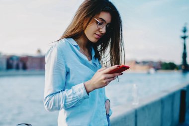 Büyüleyici giyinmiş genç bir kadın, 4G interneti kullanarak sosyal ağlarda gezmekten ve takipçilerle sohbet etmekten zevk alıyor. Hipster kızı cep telefonundan mesaj aldı.