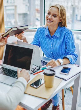 Masaüstünde dizüstü bilgisayarlarla oturan ve ortak çalışma görevlerinde işbirliği yapan iki başarılı öğrenci. Modern çalışma alanı sınavlarına hazırlanan genç ve güzel bir bayan ders kitabı arkadaşı