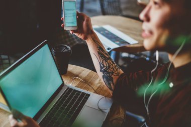 Elinde akıllı telefon tutan Çinli hippi, kulaklıklı oyuncudan müzik dinlerken cihazlar arasında yüksek hızlı bluetooth bağlantısı kullanarak dizüstü bilgisayardan medyayı paylaşıyor.