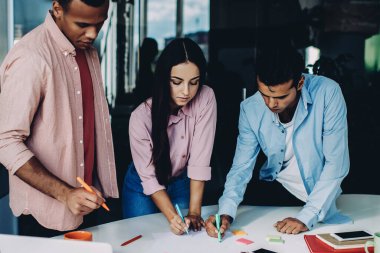 Ofis masasında dizüstü bilgisayarla beyin taraması sırasında bilgi toplayan erkek ve bayan meslektaşlar, çeşitli girişimciler çalışma sürecine ve brifinge konsantre oldular