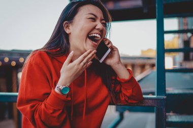 Neşeli Japon hippi kız. Yüzünde büyük mutluluğun ifadesi var. Uluslararası dostça sohbetler sırasında cep telefonunda gülüyor.
