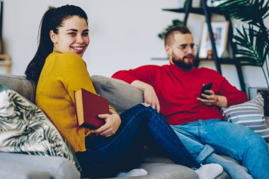 Kafkasyalı mutlu hippi kız kameraya bakıyor. Erkek arkadaşıyla rahat bir dairede vakit geçiriyor. Genç kadın evde oturup kocasıyla kanepede oturuyor ve ilginç bir kitap okuyor.