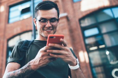 Kafkasyalı neşeli hippi adam elinde modern bir cihaz ile SMS kutusunu bilgiyle kontrol ediyor, mutlu adam veri bilgileriyle posta yazıyor ve yüksek hız bağlantısının keyfini çıkarıyor.