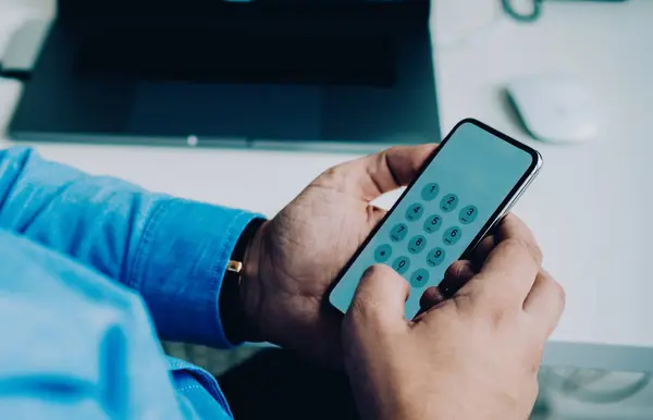 作物側ビューのビジネスマン入力Pinコード上の携帯電話に座ってデスクでラップトップ作業で現代的なオフィス — ストック写真