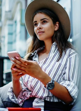 Şık şapkalı güzel bir kadın elinde cep telefonuyla blog 'da yayınlanması için makale yazmayı düşünüyor. Açık havada zaman harcayan çekici bir hippi kız akıllı telefon kullanıyor ve sohbet için 4G internet kullanıyor.