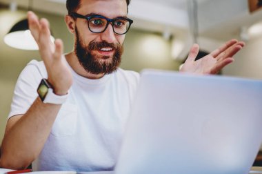 Gözlüklü, gülümseyen hippi, online yarışmayı kazanmaktan mutlu. Dizüstü bilgisayardan bildirimi kontrol ediyor. Kafkasyalı, serbest çalışan, online kazançlardan memnun.