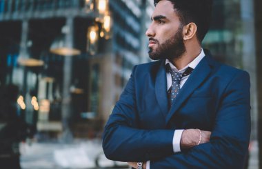 Resmi giysiler içinde yakışıklı, otoriter İspanyol bir adam. Kolları çaprazlanmış, şehir merkezinde manzarası bulanık bir pencerede dikilip düşünürken.