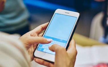 Kırpılmış kadın elleri modern akıllı telefon cihazını tutuyor ve arama bilgisine 4G internet bağlantısı kullanarak mesaj yazıyor. Dijital cep telefonundaki uygulamanın güncellenmesine seçici odaklanma