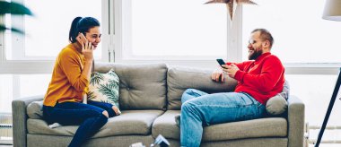 Kafkasyalı mutlu bir kadın cep telefonuyla sohbet ediyor ve erkek arkadaşı akıllı telefonla ev kablosuz bağlantısından memnun, mutlu bir çift dairede modern teknolojiyi kullanıyor.