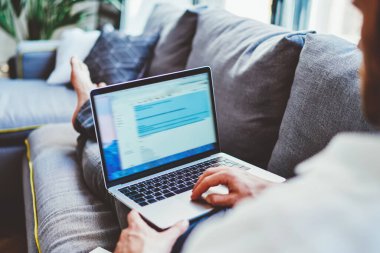 Milenyum erkeğinin antivirüs sistemini güncellemek için evde dinlenirken dizüstü bilgisayar kullanırken görüntüsü netbook üzerinden alışveriş yapan hipster bir adamın arka planı.