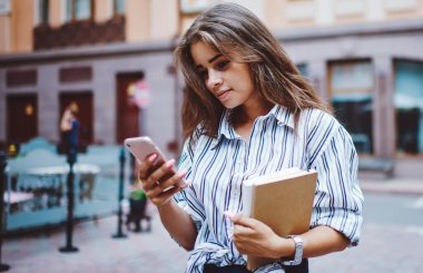 Modern cep telefonundan mesaj okuyan kız öğrenci sokakta geziniyor, çekici hippi kız akıllı telefon uygulaması ile bankacılık dengesini kontrol ediyor açık havada boş zaman geçiriyor.
