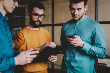 Gündelik giyinmiş bir grup genç, tatilde ofiste durup akıllı telefondan mobil uygulamaları tartışıyor. Hippi erkekler birbirleriyle iletişim kuruyor ve internet sitesinde haberlerden bahsediyorlar.