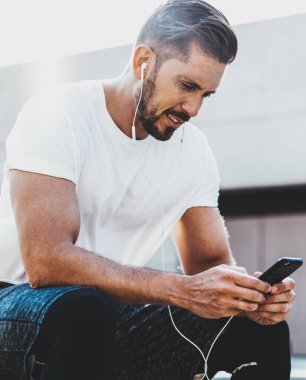 Sakallı beyaz erkek koşucu şık spor kıyafetleri giyip kardiyo eğitiminin başarısı ile ilgili bir mesaj aldı. Cep telefonunda 4G kablosuz bağlantı, sağlıklı yaşam tarzı kavramı.